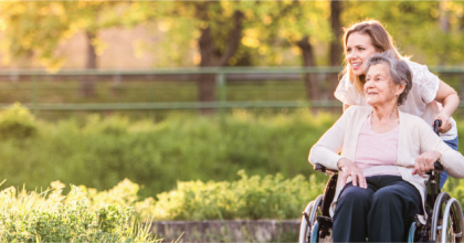 Daughter pushing her mother in a wheelchair in nature